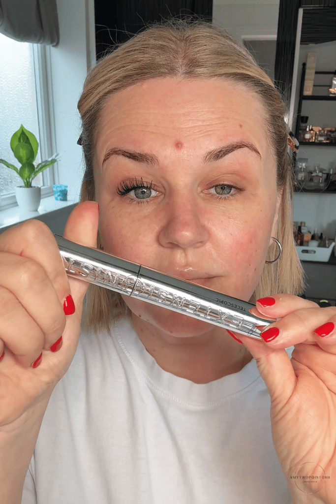 l'oreal extensionist black mascara, red nails, blonde hair, green eyes, one eye with mascara thick lashes